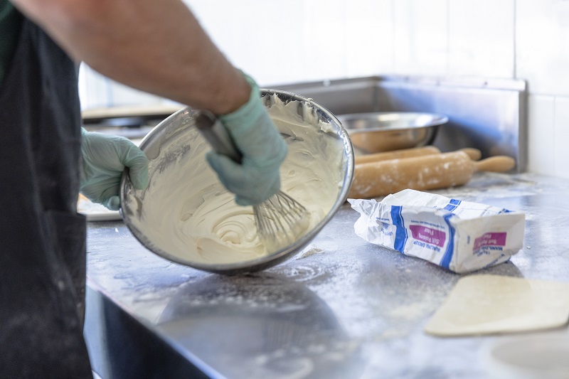Person in a kitchen environment whisking cream in bowl