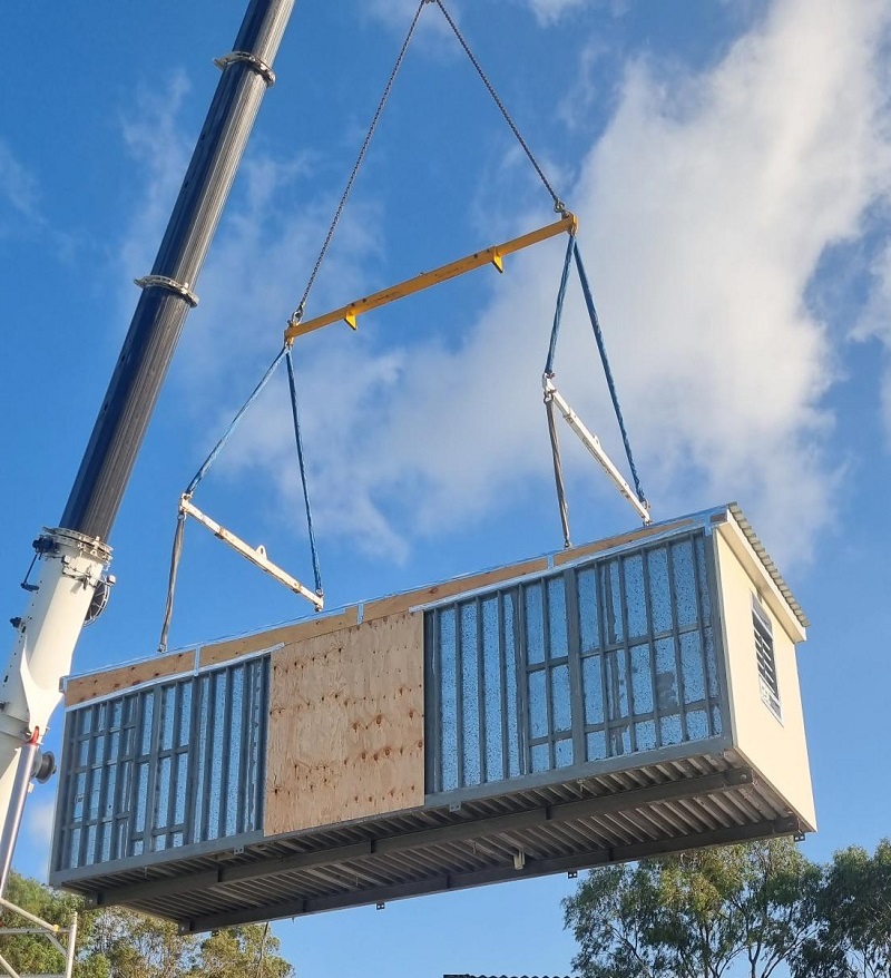 Modular building being lifted in the air by large crane