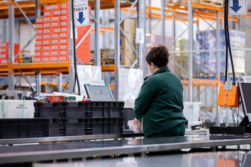 Person scanning food at a counter in a large warehouse