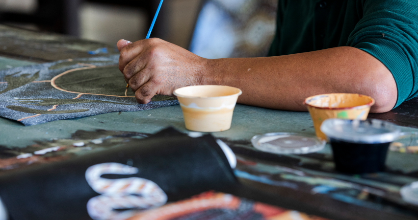 Person painting Aboriginal artwork with a paint stick