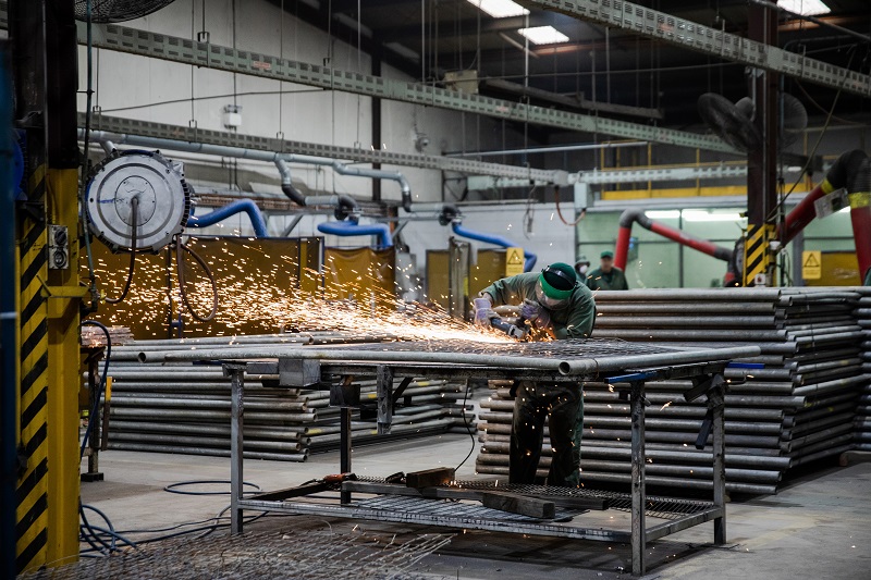 Person using an angle grinder on a piece of metal with orange sparks