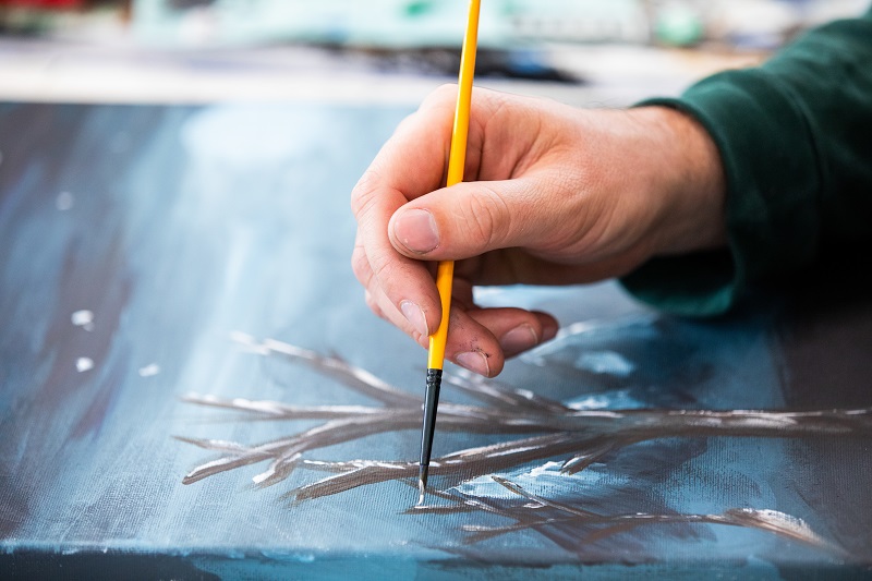 Person painting Aboriginal artwork with a paint stick