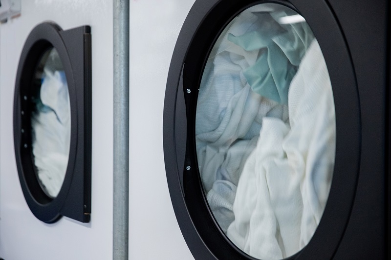 Commercial washing machines in operation with green items being washed