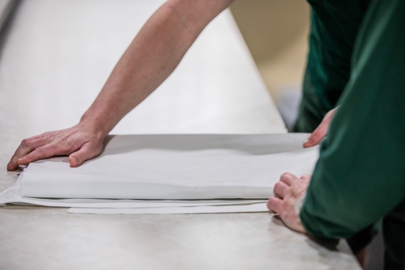 Hands folding cleaning linen on large table