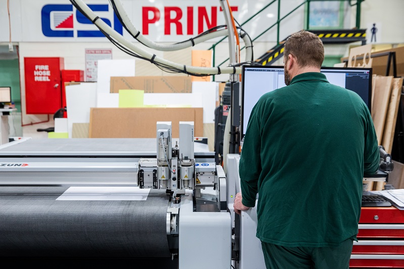 Person standing at large flat bed printer