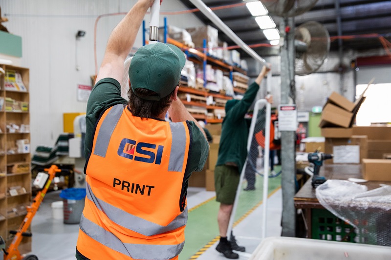 Two people working in a warehouse setting up a promotional items