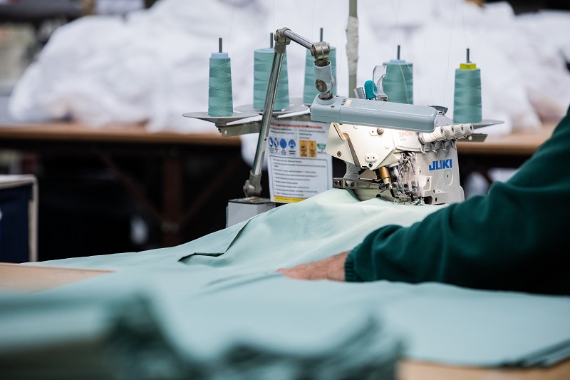 Person using a sewing machine with green material