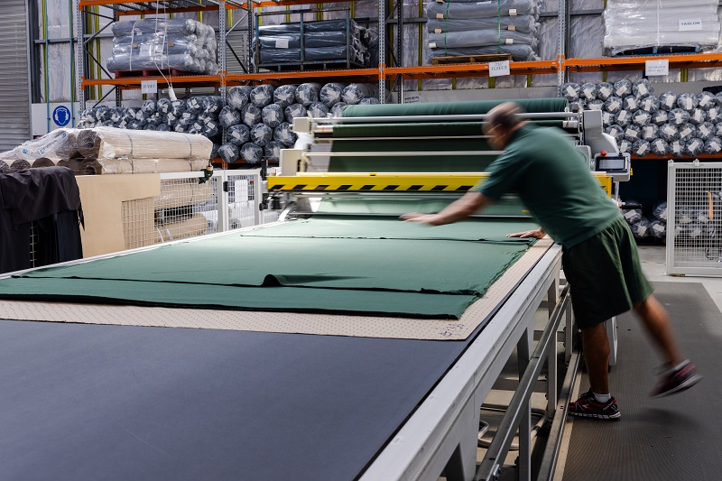 Person adjusting material on large commercial cutter 
