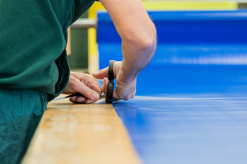 Person using scissors to cut blue vinyl