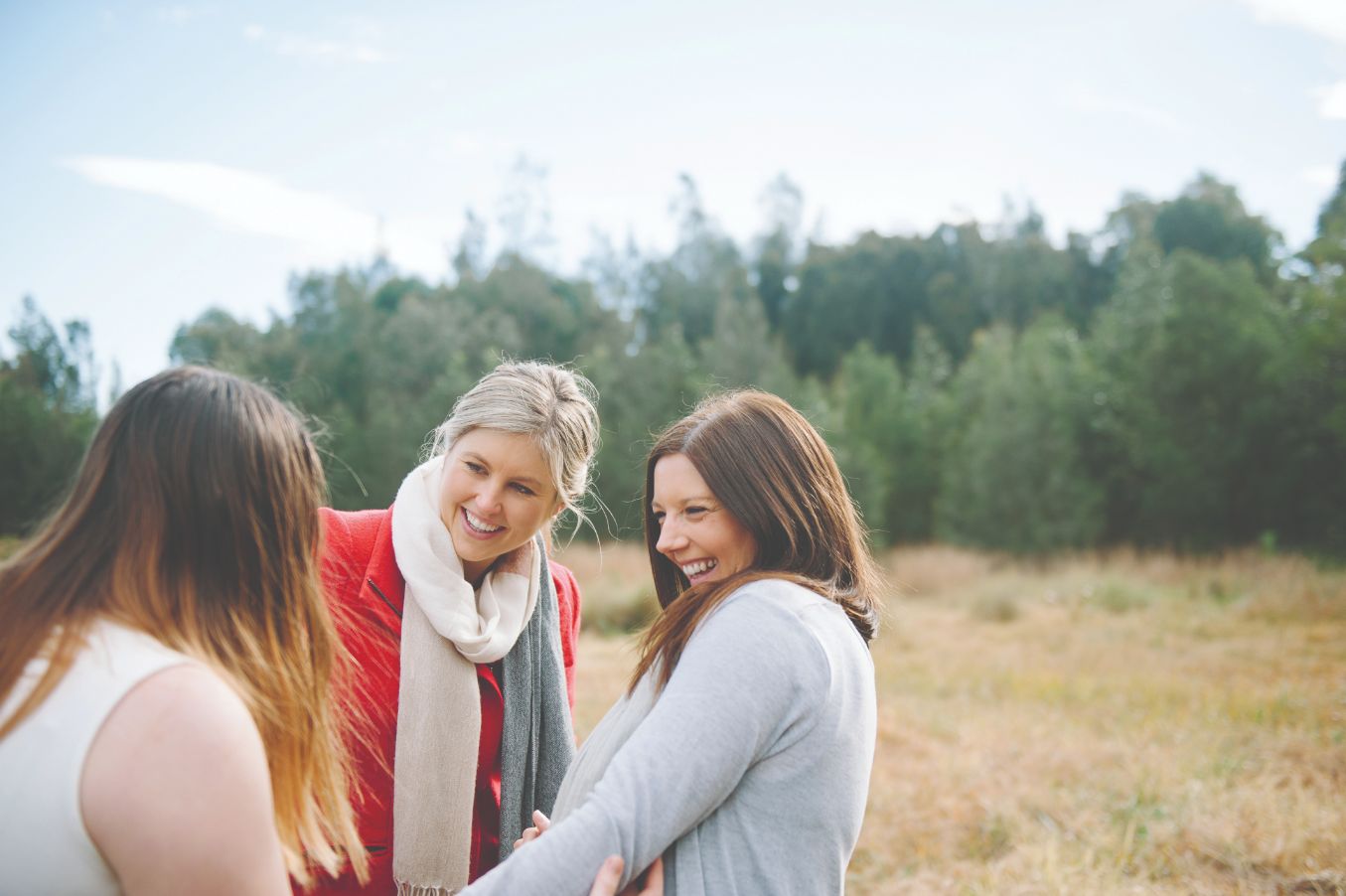 Three female adults smiling and looking at each other